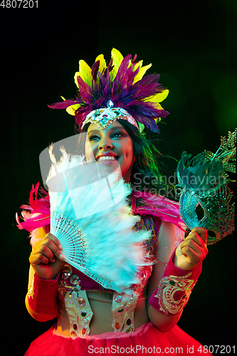 Image of Beautiful young woman in carnival mask and masquerade costume in colorful lights