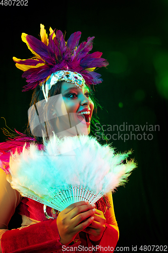 Image of Beautiful young woman in carnival mask and masquerade costume in colorful lights