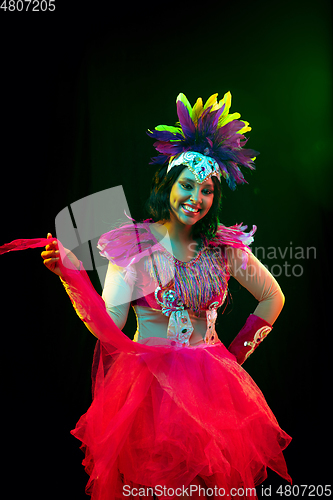 Image of Beautiful young woman in carnival mask and masquerade costume in colorful lights