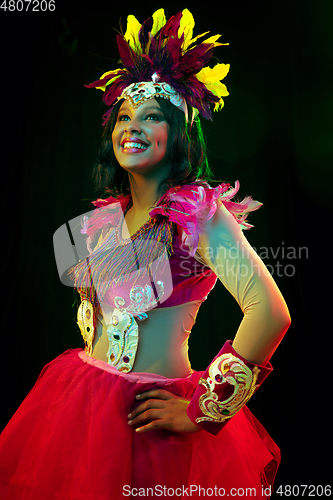 Image of Beautiful young woman in carnival mask and masquerade costume in colorful lights