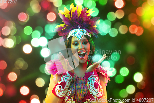 Image of Beautiful young woman in carnival mask and masquerade costume in colorful lights