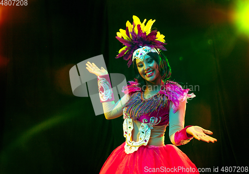 Image of Beautiful young woman in carnival mask and masquerade costume in colorful lights