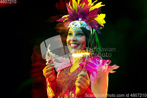 Image of Beautiful young woman in carnival mask and masquerade costume in colorful lights