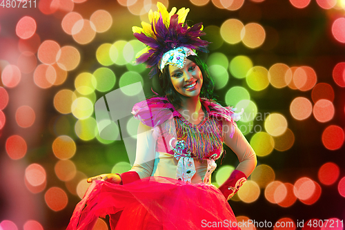 Image of Beautiful young woman in carnival mask and masquerade costume in colorful lights