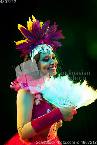 Image of Beautiful young woman in carnival mask and masquerade costume in colorful lights