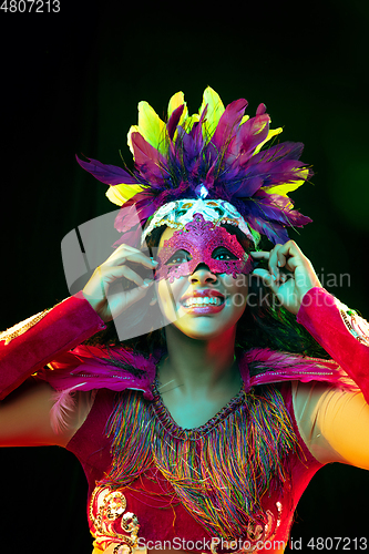 Image of Beautiful young woman in carnival mask and masquerade costume in colorful lights