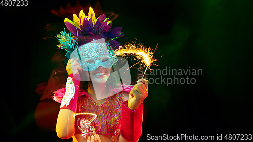 Image of Beautiful young woman in carnival mask and masquerade costume in colorful lights, flyer