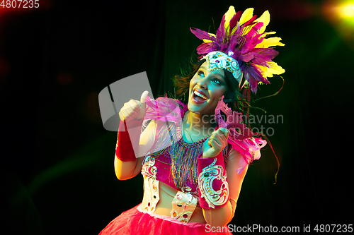 Image of Beautiful young woman in carnival mask and masquerade costume in colorful lights