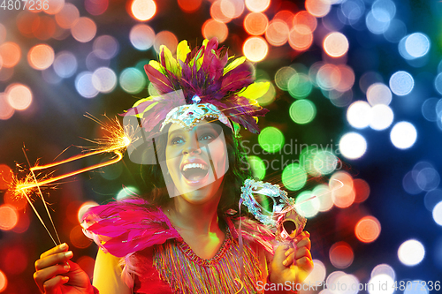 Image of Beautiful young woman in carnival mask and masquerade costume in colorful lights