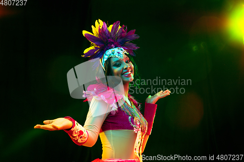 Image of Beautiful young woman in carnival mask and masquerade costume in colorful lights