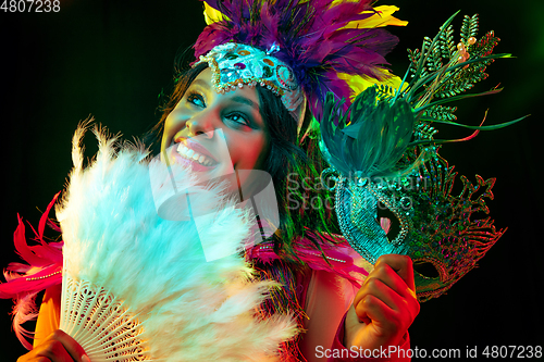 Image of Beautiful young woman in carnival mask and masquerade costume in colorful lights