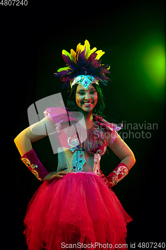 Image of Beautiful young woman in carnival mask and masquerade costume in colorful lights