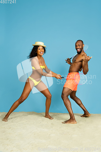 Image of Happy young couple resting on blue studio background