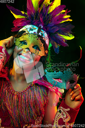 Image of Beautiful young woman in carnival mask and masquerade costume in colorful lights