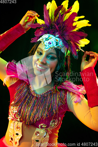 Image of Beautiful young woman in carnival mask and masquerade costume in colorful lights