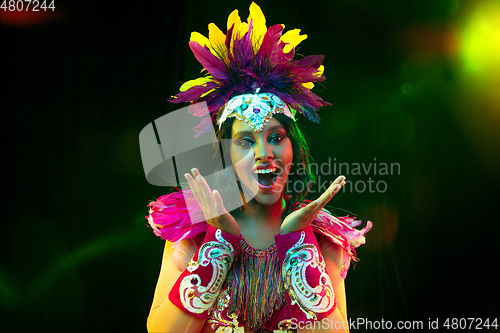 Image of Beautiful young woman in carnival mask and masquerade costume in colorful lights