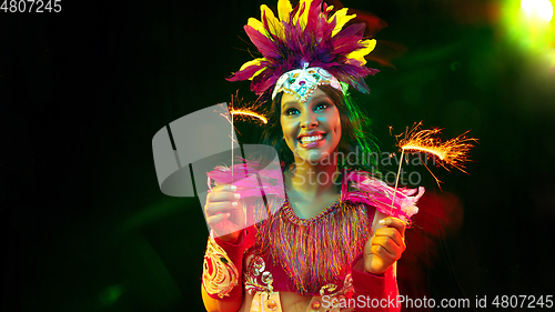 Image of Beautiful young woman in carnival mask and masquerade costume in colorful lights, flyer