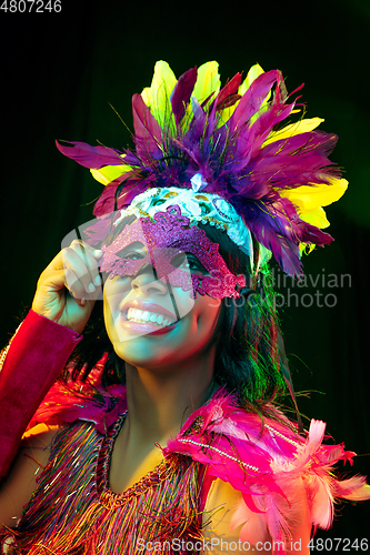 Image of Beautiful young woman in carnival mask and masquerade costume in colorful lights