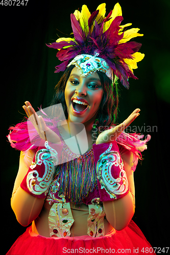 Image of Beautiful young woman in carnival mask and masquerade costume in colorful lights