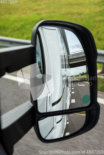 Image of Road view from the side mirror. Traveling by car