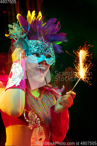 Image of Beautiful young woman in carnival mask and masquerade costume in colorful lights