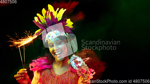 Image of Beautiful young woman in carnival mask and masquerade costume in colorful lights