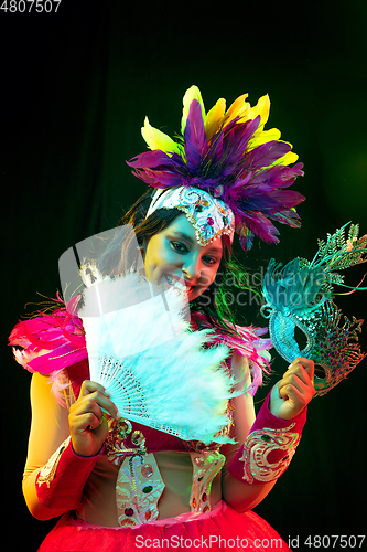 Image of Beautiful young woman in carnival mask and masquerade costume in colorful lights