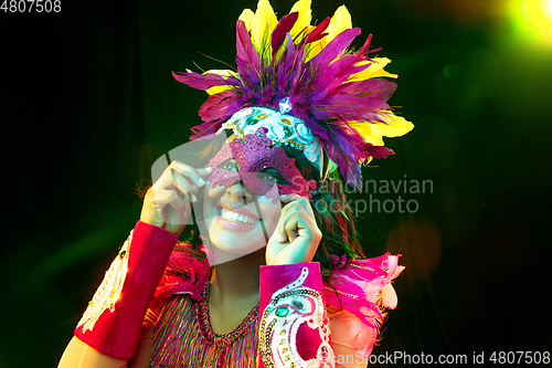 Image of Beautiful young woman in carnival mask and masquerade costume in colorful lights