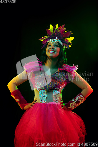 Image of Beautiful young woman in carnival mask and masquerade costume in colorful lights