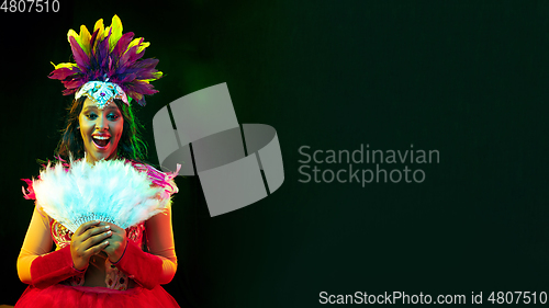 Image of Beautiful young woman in carnival mask and masquerade costume in colorful lights, flyer