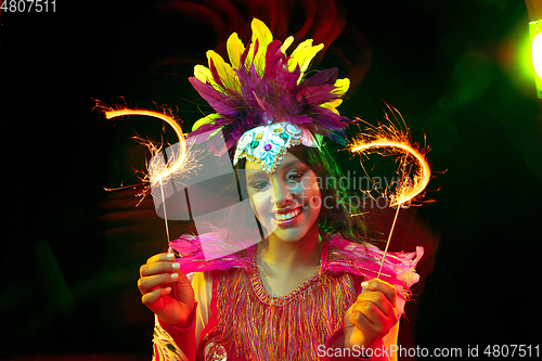 Image of Beautiful young woman in carnival mask and masquerade costume in colorful lights