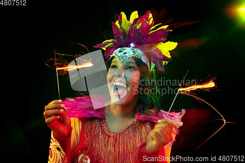 Image of Beautiful young woman in carnival mask and masquerade costume in colorful lights