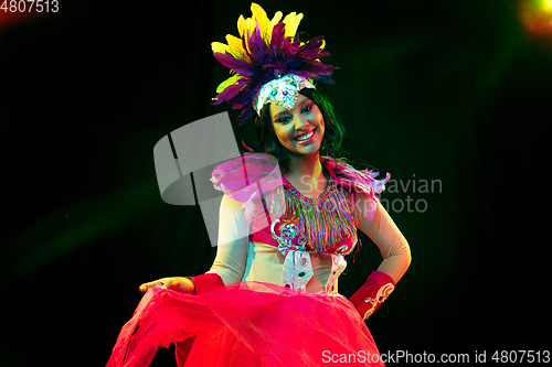 Image of Beautiful young woman in carnival mask and masquerade costume in colorful lights