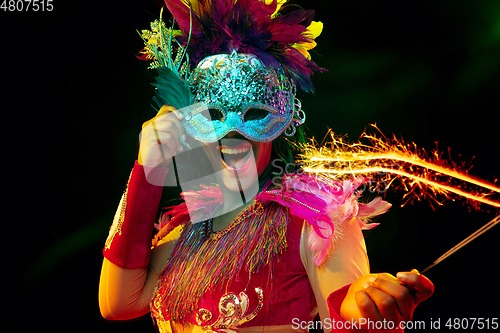 Image of Beautiful young woman in carnival mask and masquerade costume in colorful lights