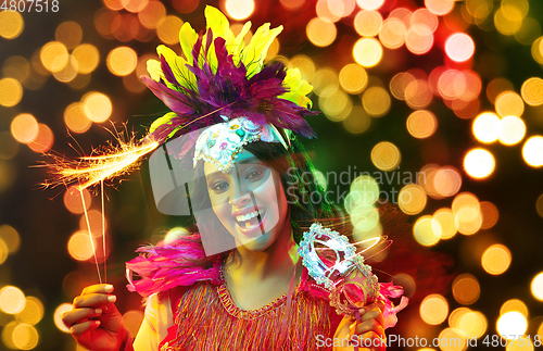 Image of Beautiful young woman in carnival mask and masquerade costume in colorful lights