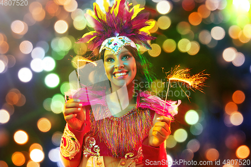 Image of Beautiful young woman in carnival mask and masquerade costume in colorful lights