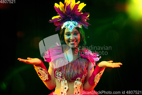 Image of Beautiful young woman in carnival mask and masquerade costume in colorful lights