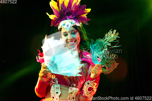 Image of Beautiful young woman in carnival mask and masquerade costume in colorful lights