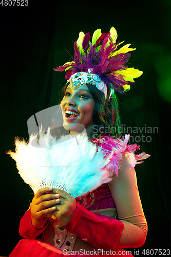 Image of Beautiful young woman in carnival mask and masquerade costume in colorful lights