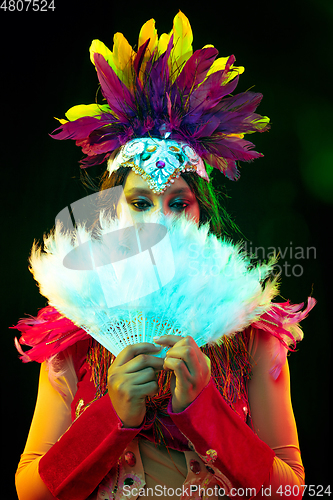 Image of Beautiful young woman in carnival mask and masquerade costume in colorful lights