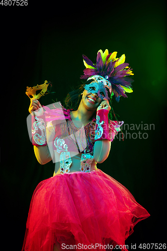 Image of Beautiful young woman in carnival mask and masquerade costume in colorful lights