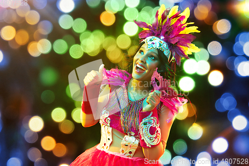 Image of Beautiful young woman in carnival mask and masquerade costume in colorful lights