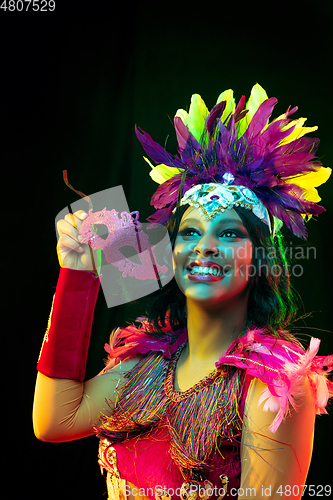 Image of Beautiful young woman in carnival mask and masquerade costume in colorful lights