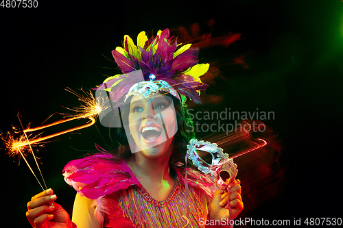 Image of Beautiful young woman in carnival mask and masquerade costume in colorful lights