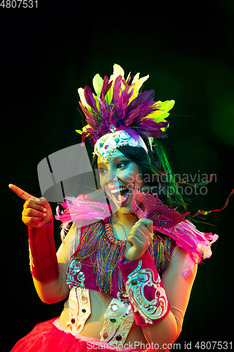 Image of Beautiful young woman in carnival mask and masquerade costume in colorful lights