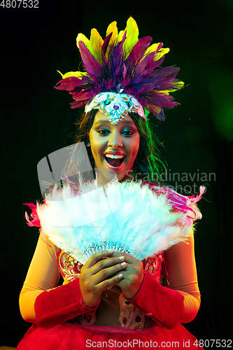 Image of Beautiful young woman in carnival mask and masquerade costume in colorful lights