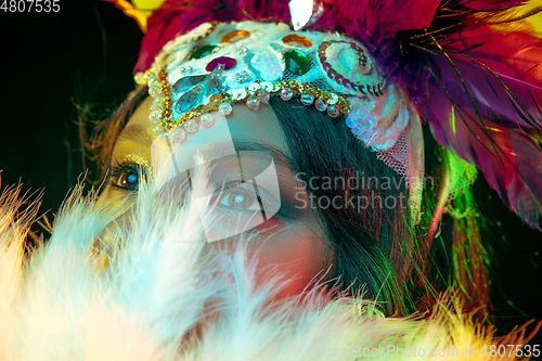 Image of Beautiful young woman in carnival mask and masquerade costume in colorful lights