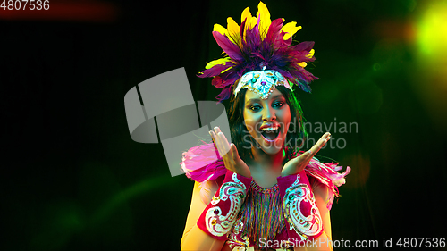 Image of Beautiful young woman in carnival mask and masquerade costume in colorful lights, flyer