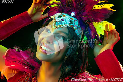 Image of Beautiful young woman in carnival mask and masquerade costume in colorful lights