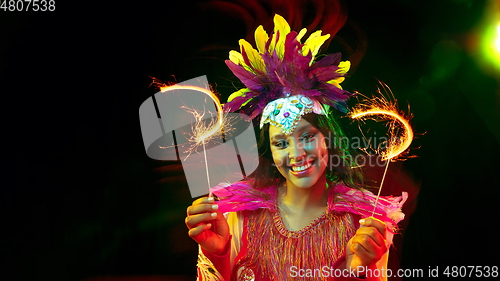 Image of Beautiful young woman in carnival mask and masquerade costume in colorful lights, flyer